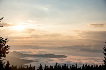 Fototapeta premium Majestic Mountain Landscape Covered in Mist with Sun Rays Breaking Through Clouds