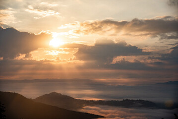 Majestic Mountain Landscape Covered in Mist with Sun Rays Breaking Through Clouds