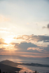 Obraz premium Majestic Mountain Landscape Covered in Mist with Sun Rays Breaking Through Clouds