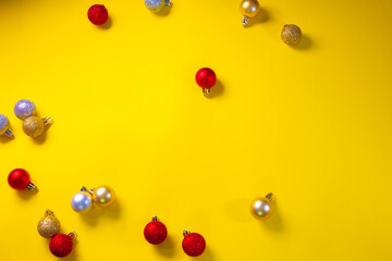 Concept of red, gold and silver Christmas balls scattered on a yellow background
