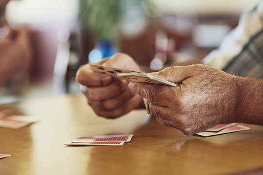 Card, game and person hands in retirement home with senior care, playing and fun on table. Cognitive, memory and activity in group with calm hobby, relax and poker for brain engagement and support