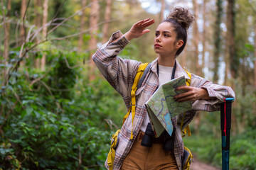 The curly-haired beauty takes a break on the forest trail, checking her map to navigate the serene autumn surroundings.
