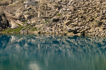 Serene mountain lake with crystal clear water reflecting rugged rocks and alpine scenery, showcasing untouched wilderness and natural beauty in a tranquil environment