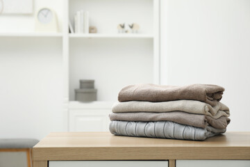 Stack of clean clothes on wooden dresser indoors