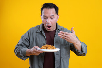 Young man reacts to hot or spicy noodles on a plate against a bright yellow background