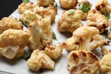 Tasty baked cauliflower and parsley on parchment, closeup