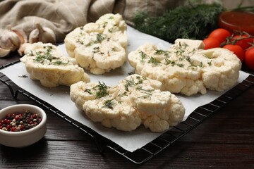 Uncooked cauliflower steaks with spices on wooden table, closeup