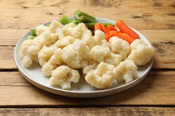 Tasty cauliflower with baby carrots and celery on wooden table, closeup