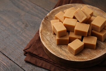 Tasty sweet caramel candies on wooden table, closeup. Space for text