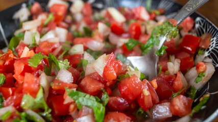 Salad cut from tomatoes, onions and greens in a deep plate close-up