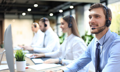 Portrait of call center worker accompanied by his team. Smiling customer support operator at work.