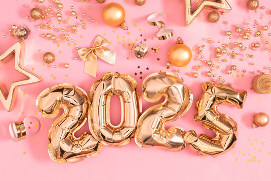Happy New Year 2025 in golden foil balloons shaped on pink background. Golden numbers inflatable balloons and glittering decorations. 