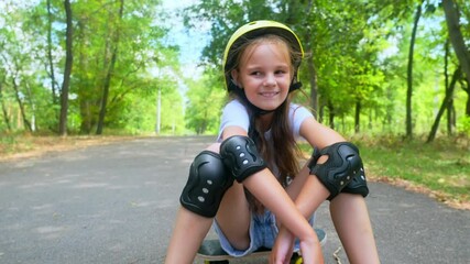 child with skateboard outdoor. Portrait little girl with a skateboard in the park. skateboarder child lifestyle looking at the camera close-up outside.