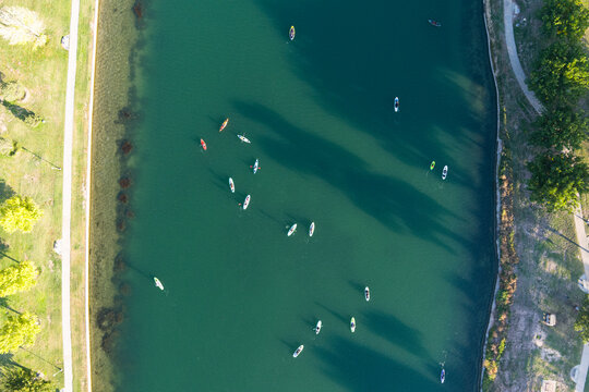 Aerial view of women paddle boarding on the tranquil Pecos River surrounded by lush trees, Carlsbad, United States.
