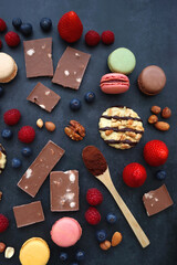 Macarons, chocolate, cookies, berries and various nuts on dark blue background. Top view.