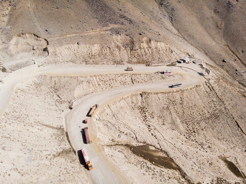 Aerial view of winding mountain road with vehicles in a rugged and arid landscape, Salang, Afghanistan.