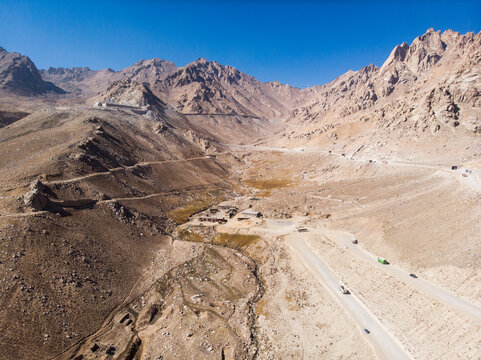 Aerial view of rugged mountains and a scenic valley with a winding road under a vast sky, Salang, Afghanistan.