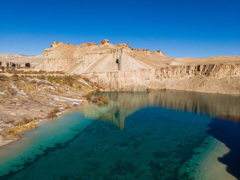 Aerial view of tranquil lake surrounded by majestic cliffs and rocky formations, Yakawlang, Afghanistan.