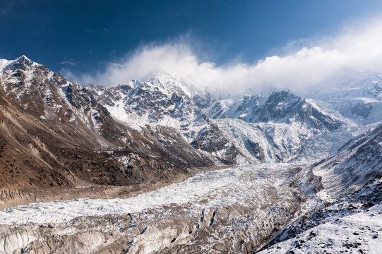 Aerial view of majestic snow-covered mountains and a glacier under a dramatic sky, Babu Sar, Pakistan.