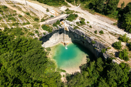 Aerial view of a breathtaking waterfall cascading into turquoise water surrounded by lush forest and rocky cliffs, Pican, Croatia.