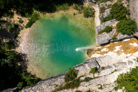 Aerial view of a tranquil waterfall cascading into a serene pool surrounded by lush forest, Pican, Croatia.