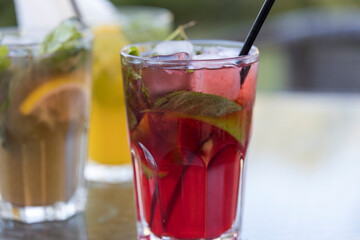 A glass of red drink with a straw in it sits on a table