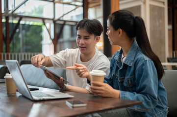 Two Asian college friends or colleagues are discussing work at a coffee shop, sharing their ideas.