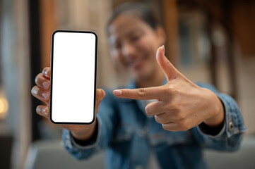 A close-up image of a woman pointing at a smartphone, showcasing the device to the camera.