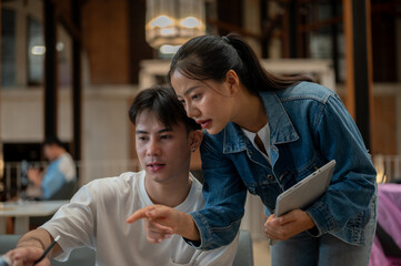 A woman is in a coffee shop with her male friend, discussing and planning a project together.