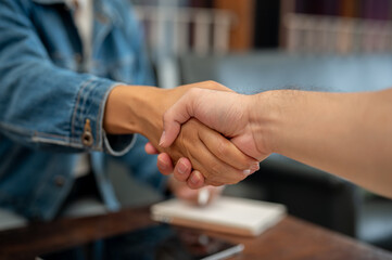 A close-up of two people shaking hands during a meeting at a coffee shop.