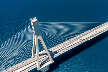 Aerial view of a beautiful suspension bridge crossing over clear blue water with a modern urban landscape, Antirrio, Greece.