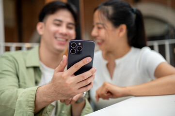 A man holding a phone to take a selfie with his girlfriend while they hang out together at a cafe.