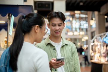 A young Asian man is texting on his smartphone while on a date with his girlfriend at a night market