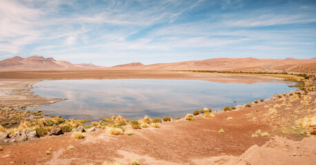 The Quisquiro Salt Flat reveals serene beauty with still waters mirroring the surrounding mountains and sky. Located in the altiplano near San Pedro de Atacama, it highlights Chile's natural charm.