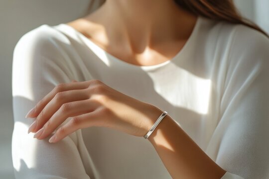 Woman wearing stylish silver bracelet posing in sunlight