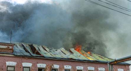 A building is on fire with smoke billowing out of the roof