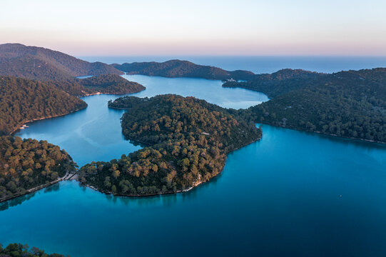 Aerial view of serene lake surrounded by lush forest and picturesque island, Pomena, Croatia.