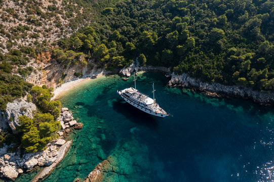 Aerial view of beautiful turquoise water with anchored sailboats along a scenic coastline and lush forest, Ston, Croatia.