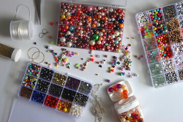 Colorful beads, letter beads, threads and other jewelry making supplies on white background. Making friendship bracelets concept. Flat lay.