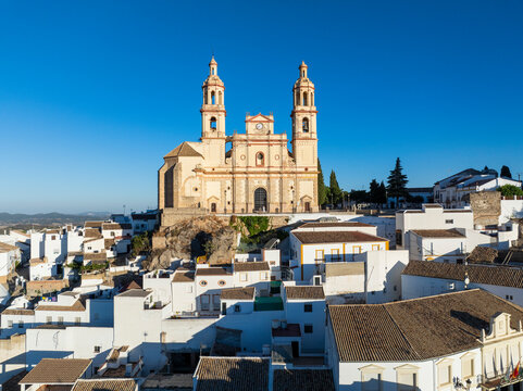 Aerial view of picturesque white buildings and rooftops surrounding a historic church, Olvera, Spain.