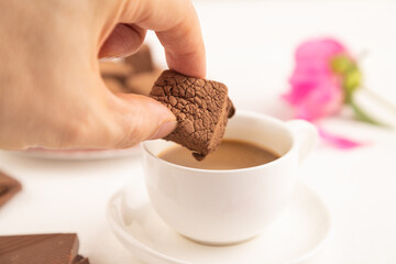 Chocolate marshmallow with cup of coffee with hand on white wooden. side view, selective focus