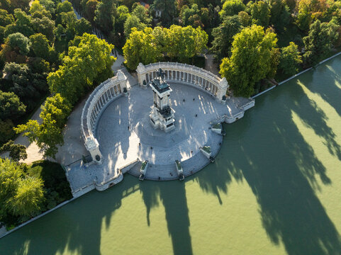Aerial view of Retiro Park with beautiful greenery, serene water reflections, and iconic monuments, Madrid, Spain.
