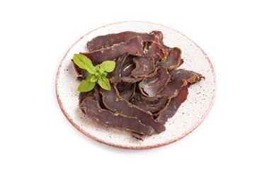 Armenian Basturma dried meat on plate with pepper and herbs isolated on white. Side view.