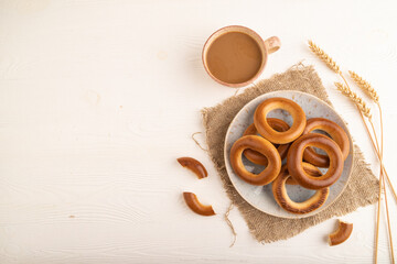 Homemade Ring Bagel with cup of coffee on white wooden background, top view, copy space.