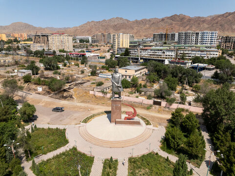 Aerial view of a beautiful urban landscape featuring a statue and modern buildings with mountains in the background, 18 mikroraion, Tajikistan.