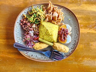 balinese yellow rice, beautifully served with lawar, string beans, satay lilit (fish), tofu, shredded chicken, onion, egg balado with chili sambal