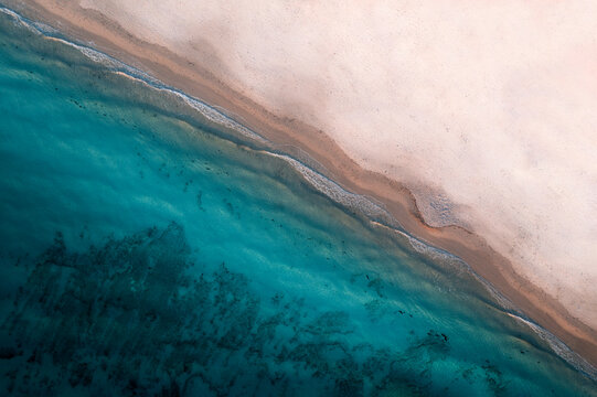 Aerial view of beach with white sand and blue water, Port Willunga, Australia.