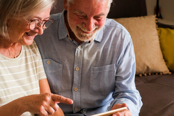 Mature couple using a tablet device for a video call with family or friends, enjoying modern technology. Elderly grandparents have fun interacting online, showcasing their engagement with the internet