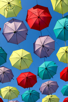 Colorful umbrellas suspended against a clear blue sky