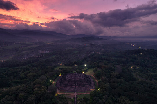 Aerial view of the majestic Borobudur temple at sunrise surrounded by lush forest, Yogyakarta, Indonesia.